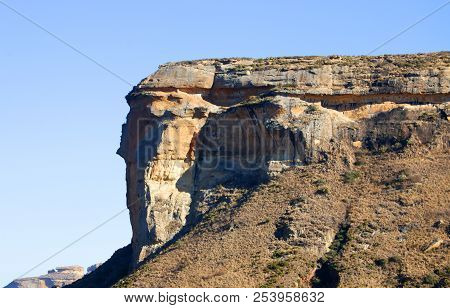 A Rocky Sandstone Mountain Jutting Out On A Blue Sky Background