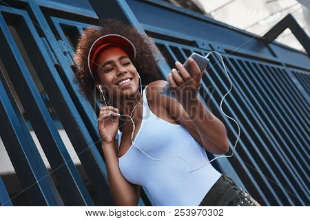 Young Woman In Tennis Visor And Earphones Free Style On The Stre