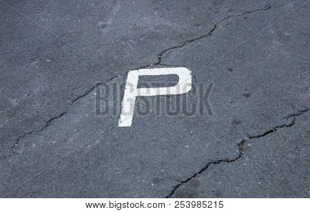 A Top View Of A Painted White P Demarcating A Parking Area On Cracked Tarmac