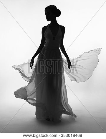 Art fashion studio photo of beautiful elegant woman in blowing dress. Fashion style of flowing dress