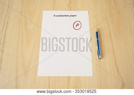 Examination Paper With Grade Test Results. Failed University Exam With Pen On The School Desk. Copys