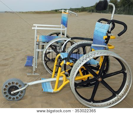 Two Special Wheelchairs With Very Large Aluminum Wheels To Move Easily On The Sand Of The Beach