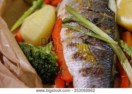Close Up Of Grilled Seabass With Vegetables And Lemon.served On Paper.