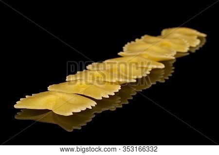 Lot Of Whole Raw Yellow Pasta Farfalle Isolated On Black Glass