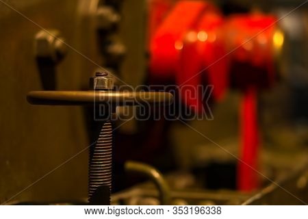 Selective Focus On Large Vintage Valve Wheel And Thread With Blurred Red And Coper Pipes And Tanks I
