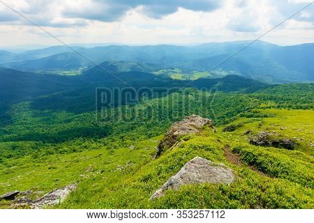 View In To The Valley From The Top Of A Mountain. Huge Rocks On The Grassy Hillside. Clouds On The S