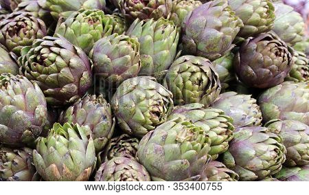 Background Of Green Artichokes For Sale In The Greengrocer Stall At The Market