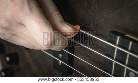 Bass Guitar Player With Pick In His Hand Closeup, Technique Lesson And Practice Theme. Playing On Ba
