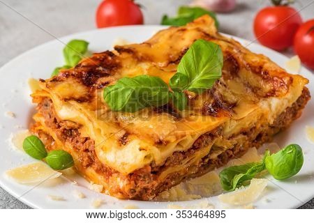 Homemade Meat Lasagna With Fresh Basil And Parmesan Cheese In A Plate On White Wooden Table. Close U
