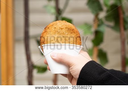 Hand Holding A Korean Traditional Street Food, Deep Fried Pancake, Hotteok, With Sweet Fillings In A