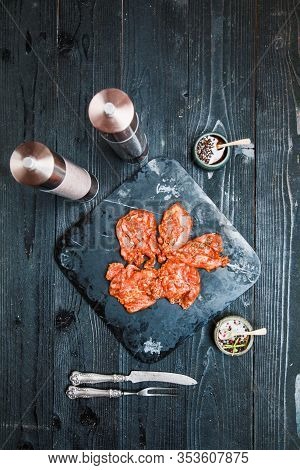 Raw Marinated Chicken Breast Fillets On Stone Plate Tray With Bbq Sauce In White Dish On Dark Old Wo
