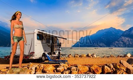 Europe travel attractive tourist girl in camping ground with camper, italian summer vacation. Beautiful young happy blonde girl in swimsuits on the beach at Garda Lake.