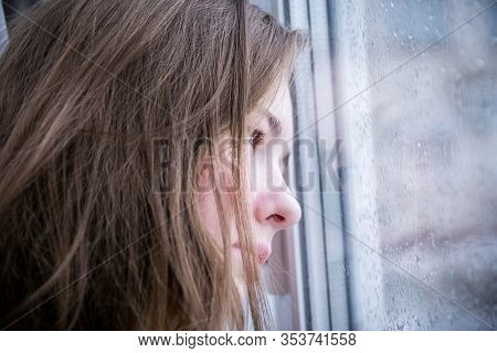 Close Up Face Of Teenage Girl. The Girl Clung To The Window With Raindrops And Was Sad. The Concept 