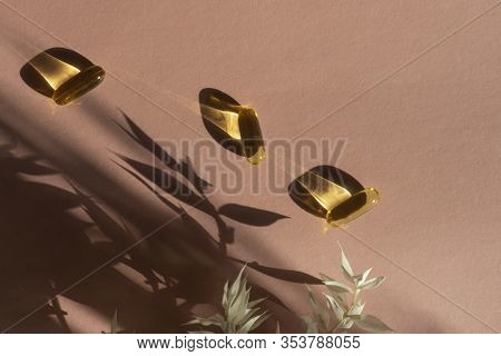 Oil Yellow Gelatin Capsules On Pink Background With Flower Shadow, Vitamins And Antioxidant Concept 