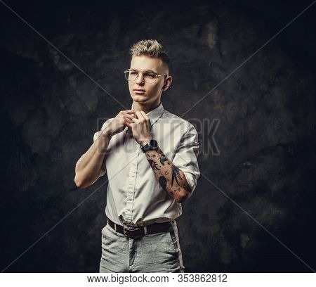 Young Adult Student Guy In A White Shirt With Tattoos On His Hand Posing In A Dark Studio, And Strai
