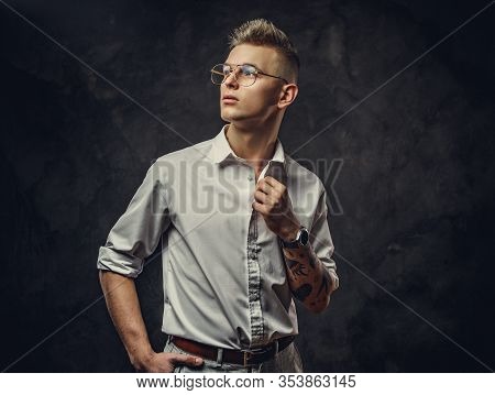 Young, Serious Looking, Adult Guy Wearing A White Shirt With Tattoos On His Hand Posing In A Dark St