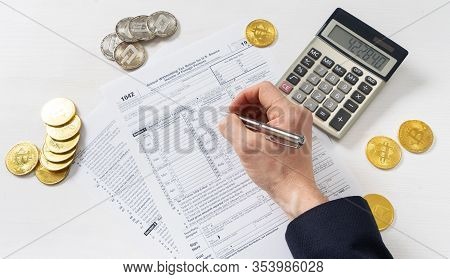 Taxation: A Man In A Jacket Fills Out A Tax Return On Trading Income On A Cryptocurrency Exchange.