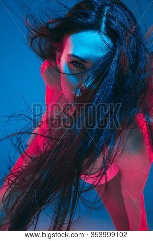 Attractive Brunette Model On Blue Studio Background In Neon Light. Beautiful Women In Underwear Posi