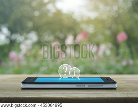 Question Mark And Information Chat Icon On Modern Smart Mobile Phone Screen On Wooden Table Over Blu