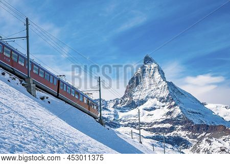 Train Passing Through Snowcapped Matterhorn Against Blue Sky