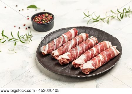 Minced Meat Wrapped In Bacon On Cast Iron Plate. Chevapchichi Or Kofta Kebab. Raw Sausages Of Ground