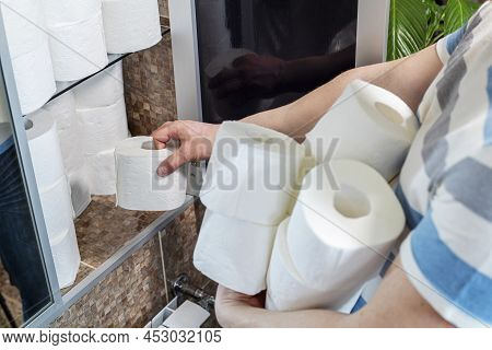 A Man Is Stocking Up Toilet Paper At Home. Consumer Buying Panic About Coronavirus Covid-19 Concept.