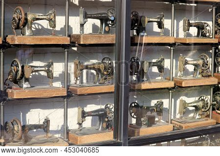 April 10, 2022 In Cabazon, Ca:  Antique Sewing Machines On Display At Window Shelves In Front Of A R