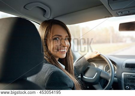 Driver Turns To Passenger Seat And Smiles At Camera. Happy Woman Taxi Driver Sitting In Car Holding 