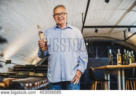 Portrait Of Senior Man Who Owns Winery. He Is Examining Quality In His Wine Cellar. Industry Wine Ma