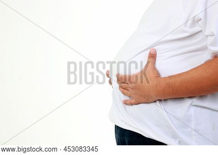 A Fat Asian Man In A White T-shirt Stood Holding His Belly. He Felt Uncomfortable, Abdominal Distens