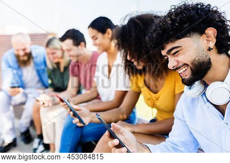 Group Of Millennial Friends Using Smartphones Sitting Outdoors - Young Diverse People Watching Socia