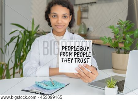 Closeup On Wooman Holding A Card With Text People Buy From People They Trust, Business Concept Image