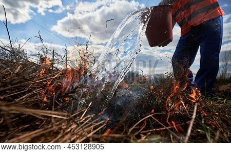 Firefighter Ecologist Fighting Wildfire In Field With Cloudy Sky On Background. Close Up Of Male Env