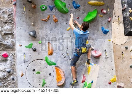 The Climber Trains On The Artificial Rock Wall With Insurance In Bouldering Gym, April 2022, Prague,