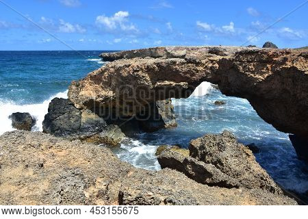 Stunning Natural Arched Lava Rock Bridge Along The Coast Of Aruba.