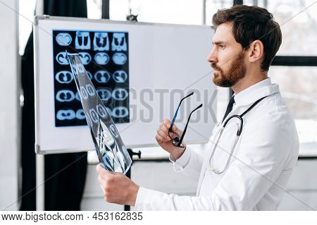 Smart Concentrated Caucasian Doctor In A Medical Uniform, A Pulmonologist, A Therapist, Stands In Ho