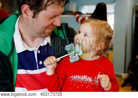 Cute Toddler Girl And Father With Cloverleaf Lollipop In Irish Pub Or Cafe. Child And Dad, Young Man