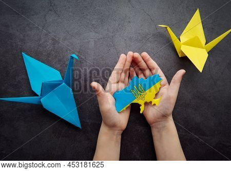 Hands Holding The Shape Of Ukraine Border With Color Flag And Paper Birds. Stand With Ukraine.