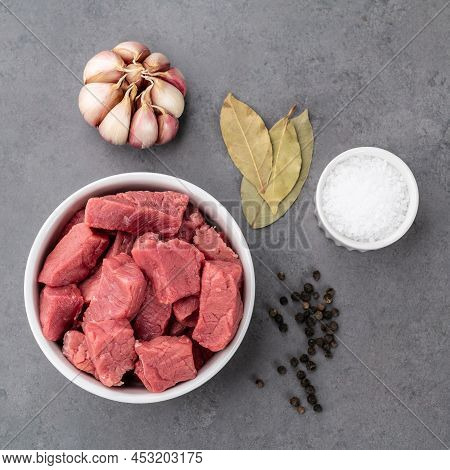 Chopped Topside Meat In A Bowl With Seasonings Over Stone Background.