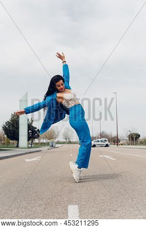 Young Adult Woman Dancing Break Dance In The Street. African Teenager In Stylish Trendy Blue Outfit 