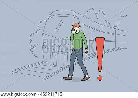 Young Man Talking On Phone Crossing Tracks While Train Is Approaching. Careless Guy Speak On Cellpho