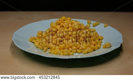 Yellow Corn Is Scattered On The Table. A Can Of Canned Corn With Juice Is Open And Stands On A Woode