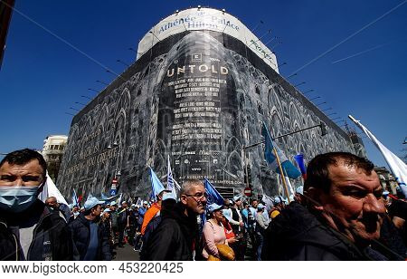 Bucharest, Romania - April 06, 2022: Protesters At A Union Rally Pass By An Advertisement For Untold