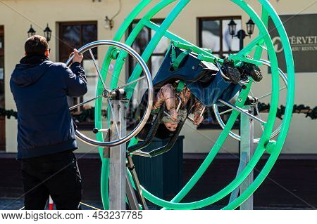 Dobele, Latvia - April 17, 2022: Kids Enjoy The Extreme Attraction Aerotrim - A Human Gyroscope With