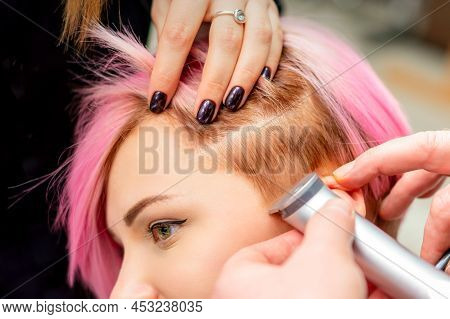 Hairdresser Shaves Female Temple With Pink Hair By Electric Shaver In A Hairdresser Salon, Close Up