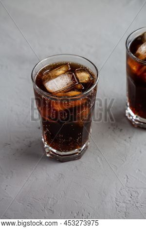Cold Refreshing Dark Cola With Ice Cubes On A Gray Background, Side View.