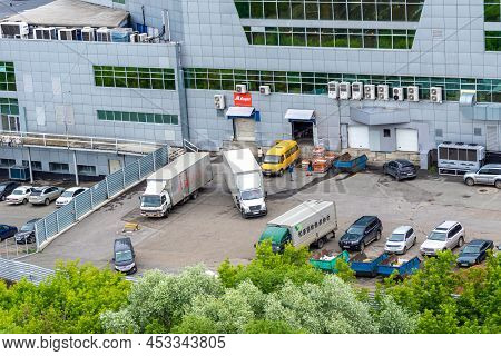 Kemerovo, Russia - June 24, 2021. A Large Building With Cars And Unloading Trucks, The Backyard Of A