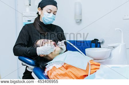 The Stomatologist Cleaning A Patient's Teeth, A Dentist Cleaning A Patient's Mouth, A Dentist Cleani