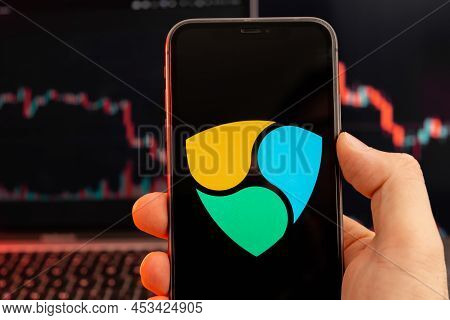 Nem Xem Cryptocurrency Logo On The Screen Of Smartphone In Mans Hand With Downtrend On The Chart On 