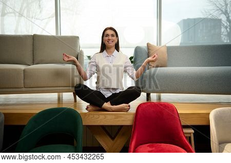Peaceful Relaxed Middle-aged Beautiful Caucasian Woman Seller In A Furniture Store, Sits In A Lotus 